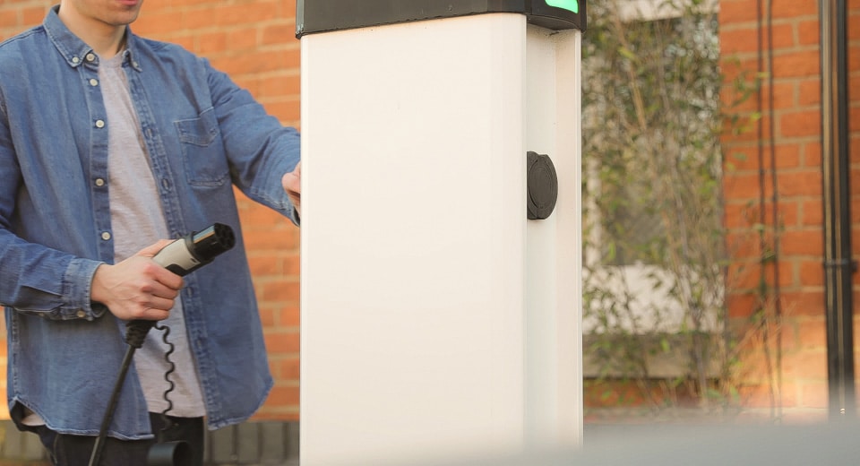 personne en train de repositionner un câble de recharge sur une borne de recharge de véhicules électrique